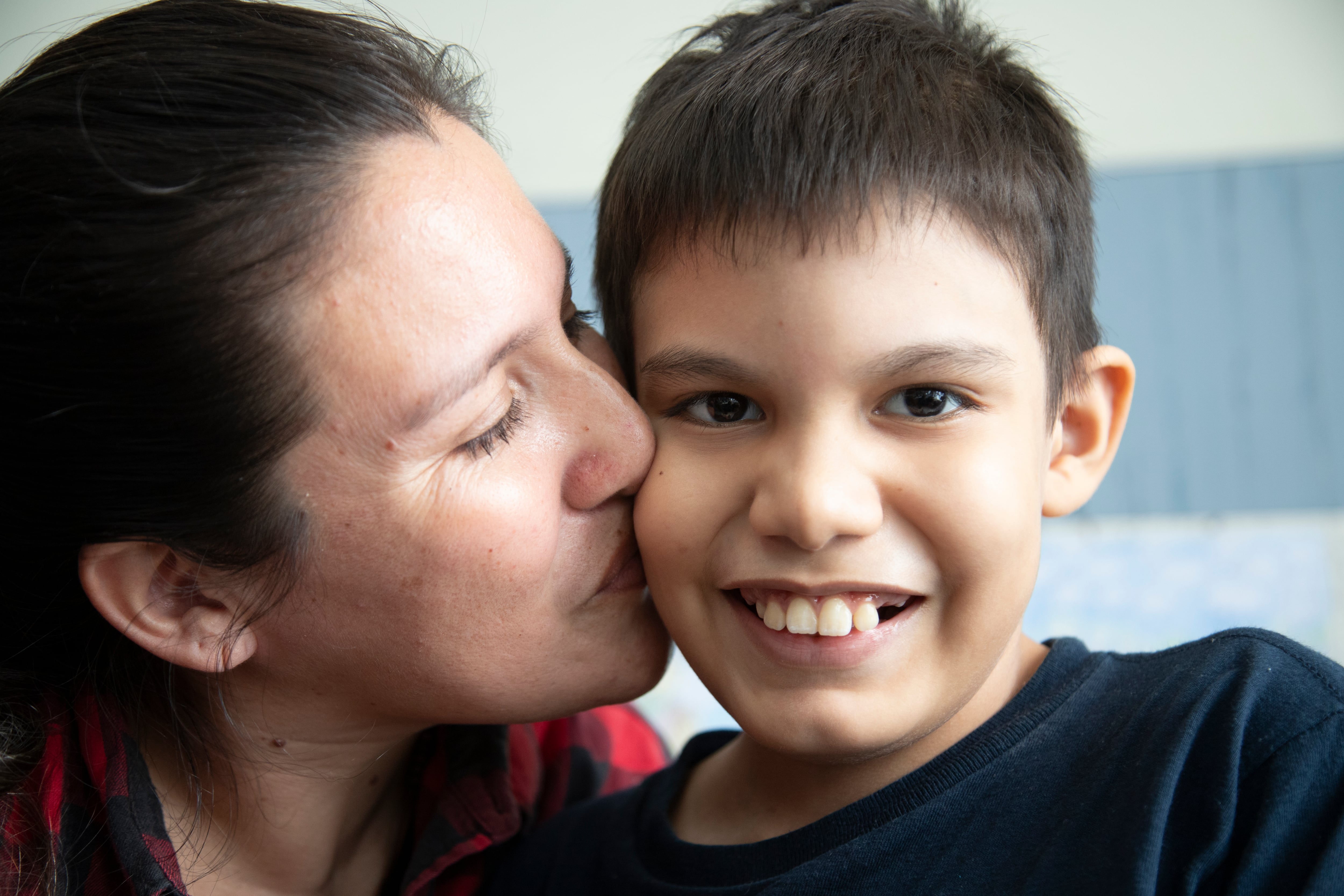 Una madre besa a su hijo en la mejilla tras la intervención médica de EsSalud que le permitió reconstruir su esófago. (EsSalud)