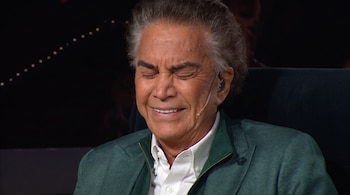 José Luis Rodríguez con los ojos cerrados, camisa blanca, chaqueta verde y un micrófono de diadema.