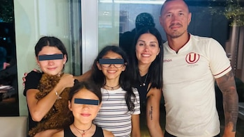 Un hombre, una mujer, tres niñas y un perro de color marrón posan juntos y sonriendo. Una niña sujeta al perro. Dos niñas tienen los ojos cubiertos por barras oscuras