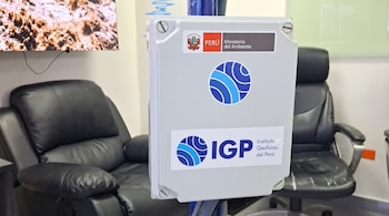 Caja gris con logotipos del Ministerio del Ambiente y del Instituto Geofísico del Perú, situada frente a dos sillones negros de oficina.