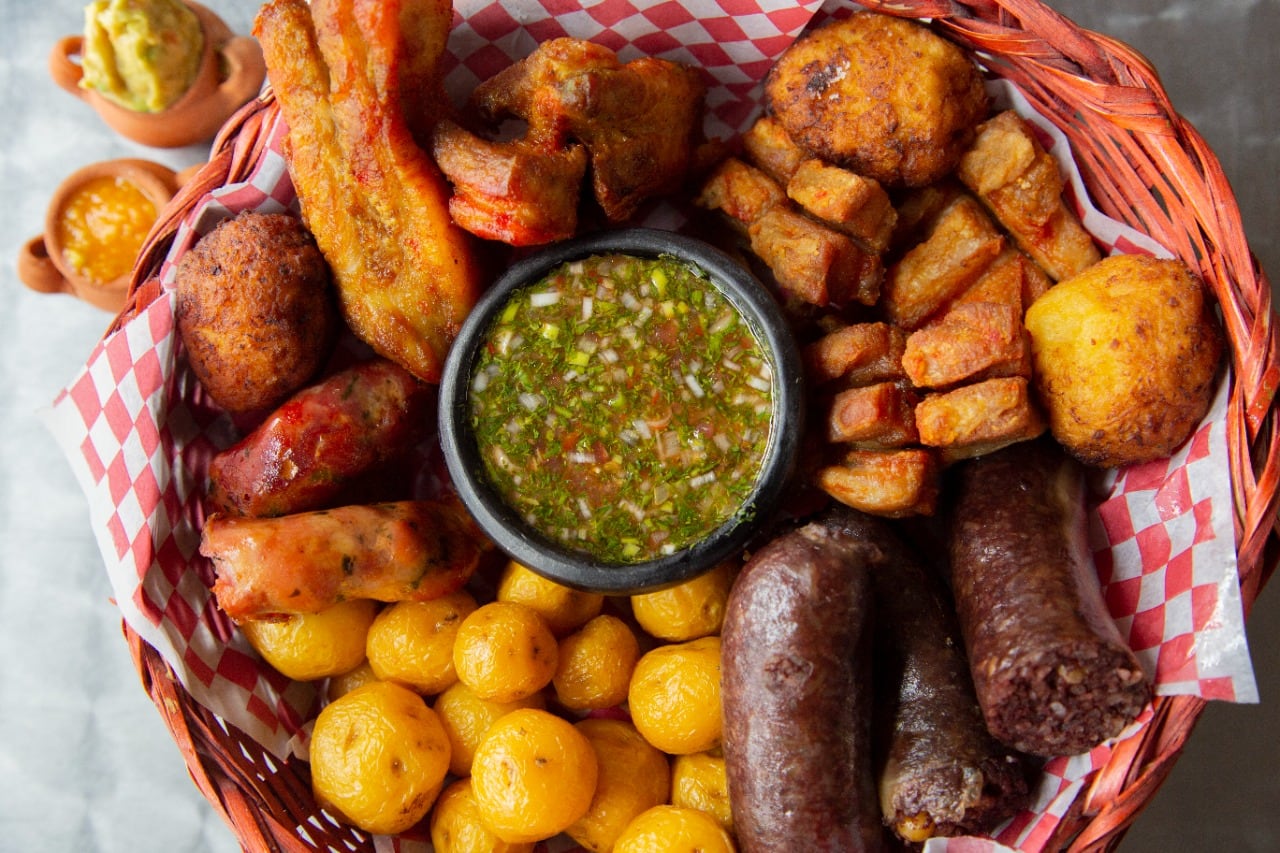 La receta tradicional de fritanga reúne carnes como chicharrón, chorizo y morcilla con acompañamientos como papa criolla y plátano - crédito Ipes