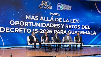 Cinco personas sentadas en un escenario frente a una pantalla gigante azul con texto sobre seguros, ante una audiencia en un auditorio