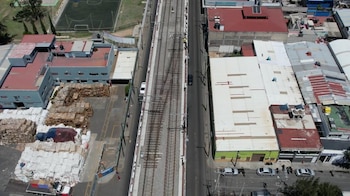Vista aérea de vías de metro elevadas entre calles con automóviles y edificios de la ciudad