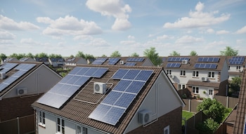 Conjunto de casas con techos de tejas marrones, paneles solares azules y unidades de aire acondicionado, bajo un cielo con nubes y árboles.