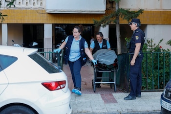 Miembros de los servicios funerarios retiran uno de los cuerpos hallados muertos este viernes por arma de fuego en Málaga.