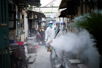 Workers in protective suits disinfect