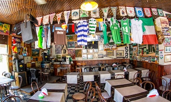 Mesas y sillas en el salón de un restaurante con camisetas deportivas, banderines, cuadros y altavoces colgados en las paredes