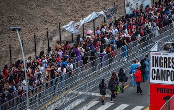 Una multitud de personas hace fila entre vallas metálicas de seguridad frente a un cartel de ingreso a la zona de campo de un estadio