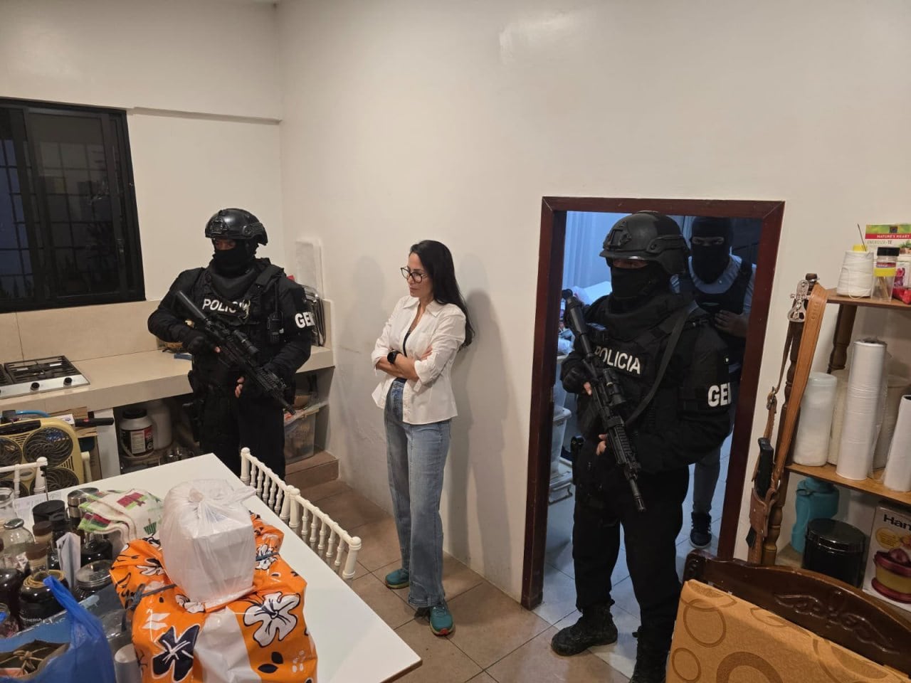 La política ecuatoriana Luisa González permanece junto a agentes de las fuerzas especiales de la policía dentro de un inmueble.