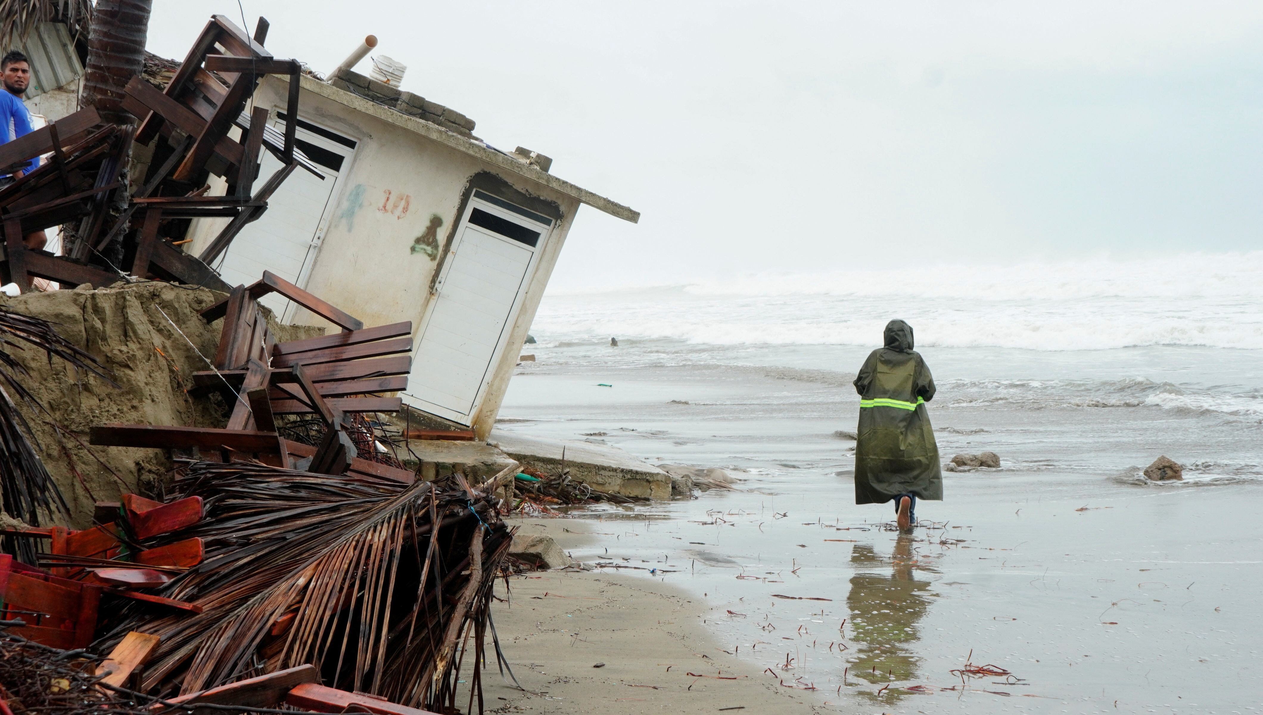 A person walks past debris on Revolcadero beach as tropical storm Dalila continues to move along the Pacific coast, in Acapulco, Mexico, June 14, 2025. REUTERS/Javier Tinoco