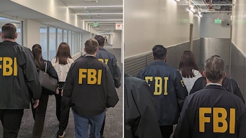 Varias personas con chaquetas oscuras con la sigla FBI en la espalda caminan por un pasillo junto a una mujer esposada