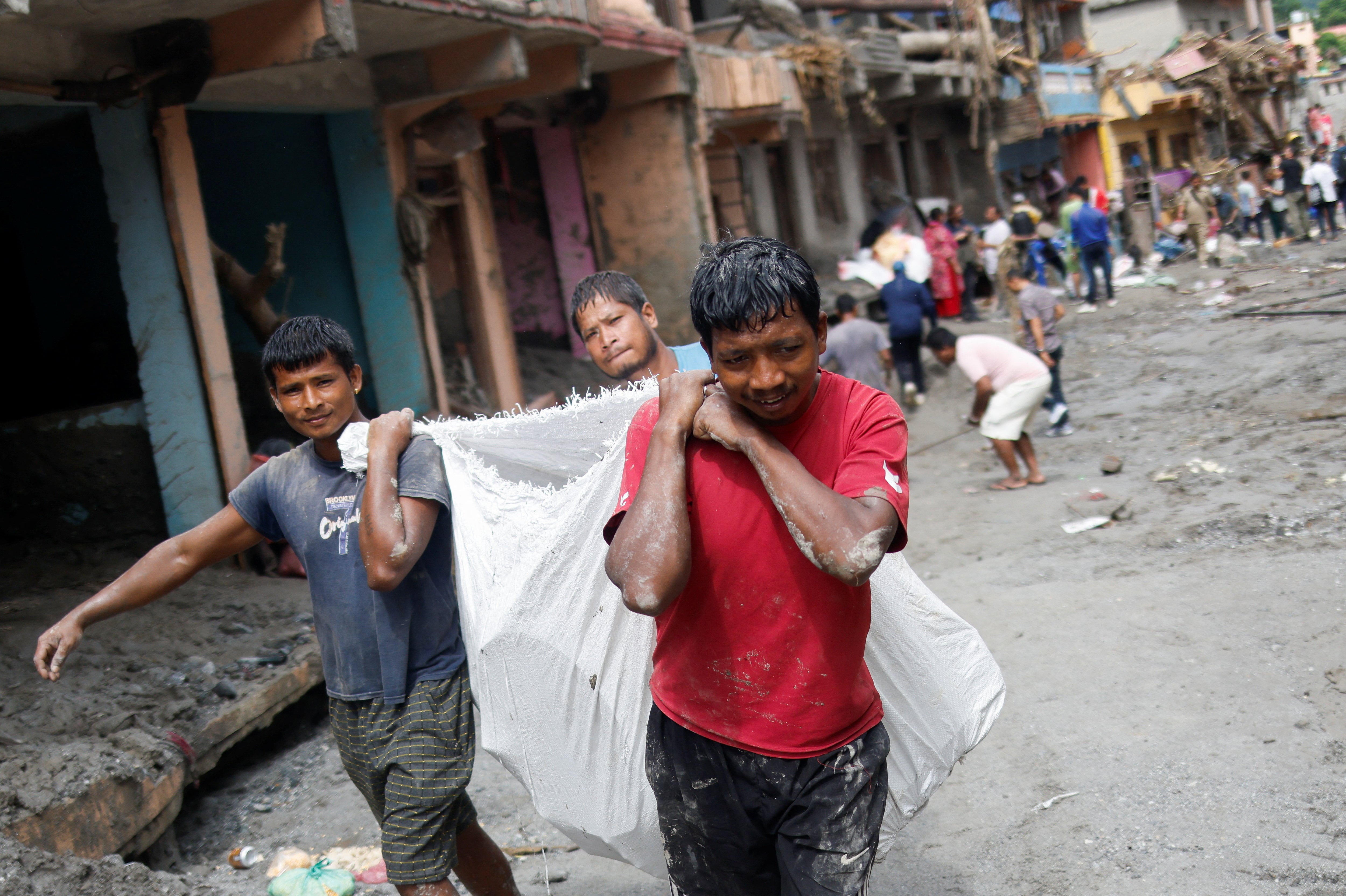 Personas transportan pertenencias rescatadas de casas dañadas tras las inundaciones repentinas y el deslizamiento de tierra en Devighat, distrito de Nuwakot, Nepal, 29 de agosto de 2026. REUTERS/Adnan Abidi