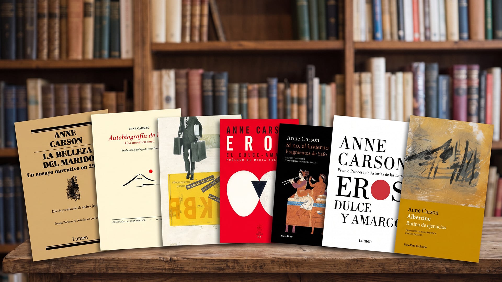 Varias publicaciones en español de la escritora Anne Carson se exhiben sobre una mesa frente a una estantería repleta de libros.
