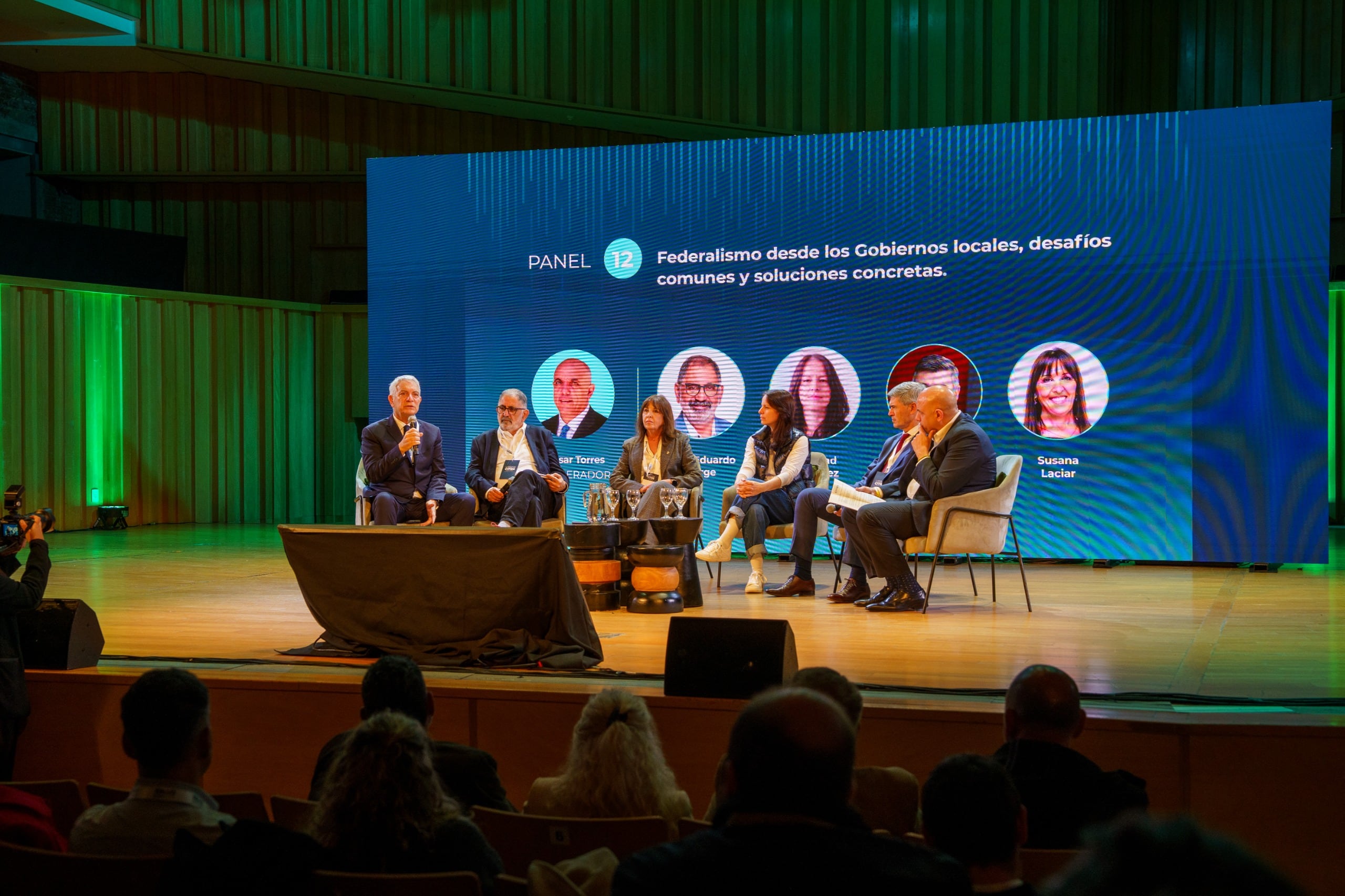 Un grupo de funcionarios e intendentes debate sobre el federalismo desde los gobiernos locales durante un encuentro institucional en un auditorio.