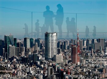 Las siluetas de varios turistas se reflejan sobre el paisaje urbano de Tokio (Japón), en una imagen tomada desde una azotea. EFE/Kimimasa Mayama/Archivo