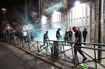 La gente pasa caminando mientras una granada aturdidora explota en medio de la tensión con los palestinos, durante el mes sagrado de ayuno musulmán del Ramadán, en Jerusalén, 24 abril 2021.
REUTERS/Ronen Zvulun