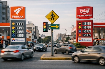 Dos estaciones de servicio, Primax y Petroperú, frente a frente en una calle de Lima con paneles de precios de combustible y vehículos en movimiento.