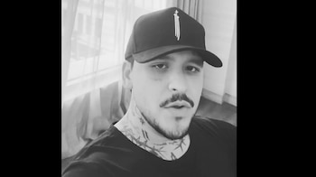 Fotografía monocromática de Hunter Metts mirando a cámara. Viste gorra negra, camiseta oscura y tiene tatuajes en la cara y el cuello