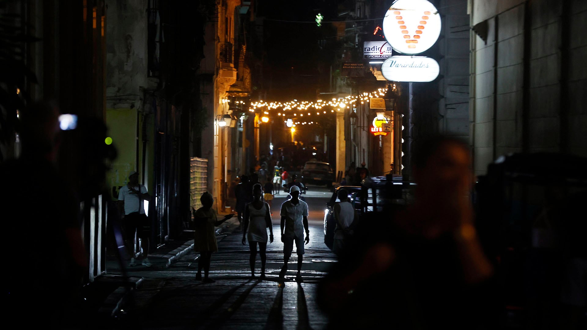 Personas caminan por una calle adornada con luces de Navidad este domingo, en La Habana (EFE/Ernesto Mastrascusa)