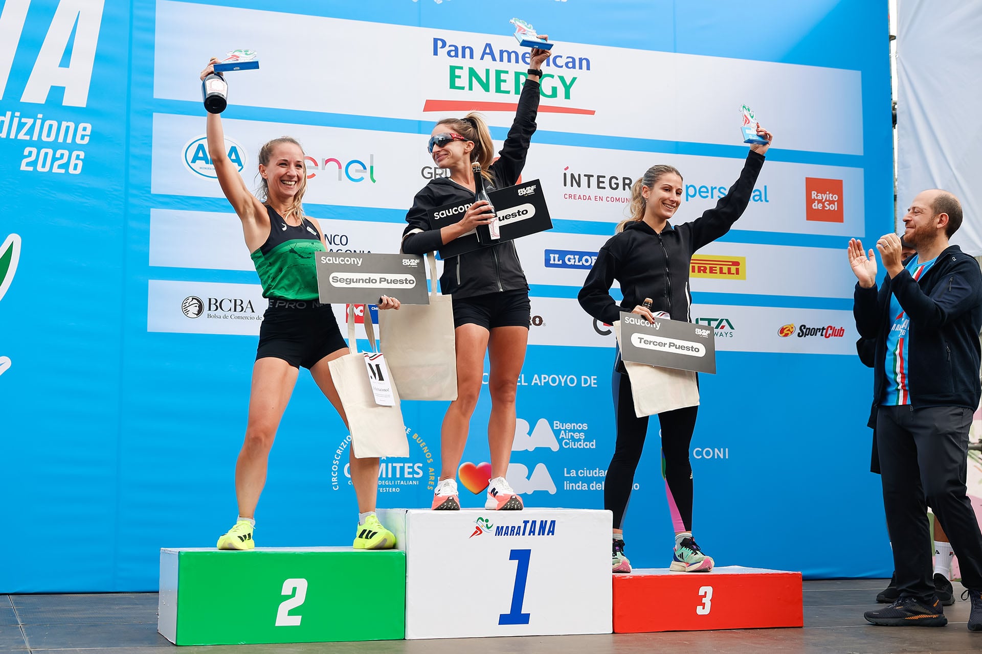 Las atletas ganadoras de MaraTANA 2026, en primer, segundo y tercer lugar, posan sonrientes en el podio con sus trofeos y premios