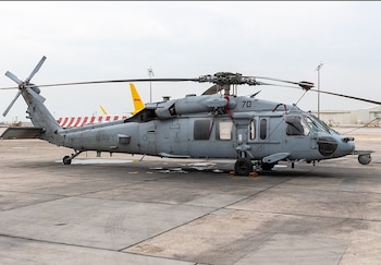 Helicóptero Sikorsky S-70 de la Armada gris oscuro estacionado en una pista de concreto. Muestra el rotor principal, rotor de cola y la inscripción 'NAVY' en el fuselaje