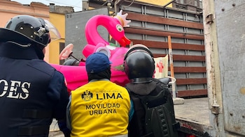 Agentes con cascos y un fiscalizador con chaleco amarillo de la Municipalidad de Lima suben un vehículo rosado a un camión