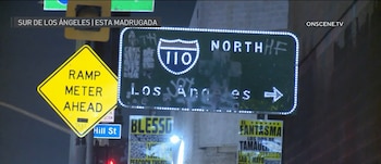 Una señal luminosa de la Interestatal 110 "NORTH Los Angeles" y una señal amarilla de "RAMP METER AHEAD" en una carretera oscura de Los Ángeles