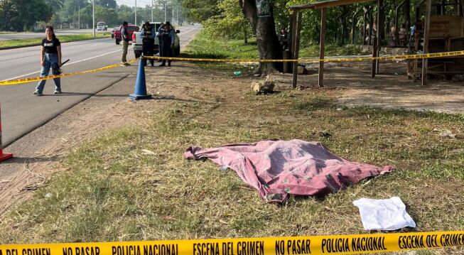 Maniatado, con heridas de arma de fuego y acompañado por un frío escrito que decía «por meterse con mujeres casadas», así hallaron el cadáver de un individuo no identificado en la carretera de Puerto Cortés (Cortesía: Tiempo HN).