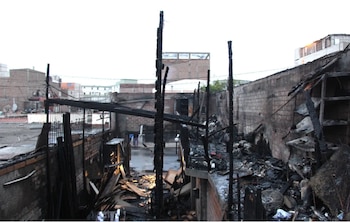 Estructura carbonizada de un inmueble con vigas quemadas, paredes de ladrillo cubiertas de hollín y escombros en el suelo