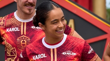 Una mujer con el cabello recogido sonríe vistiendo una camiseta deportiva roja con el texto Karol y el logo de Exatlón.