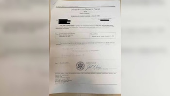 Un documento legal impreso en papel que incluye un sello oficial, una firma y datos tapados con rectángulos negros
