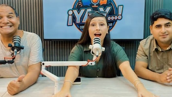 Tres personas, dos hombres y una mujer, sentadas en una mesa frente a micrófonos en un estudio con el logo '¡Ya, y!' al fondo