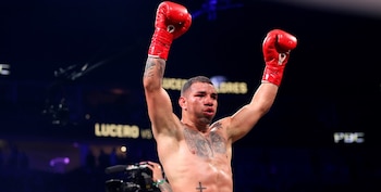 Boxeador Ismael Flores con guantes rojos levantados en señal de victoria, torso desnudo con tatuajes y marcas en la cara, fondo oscuro