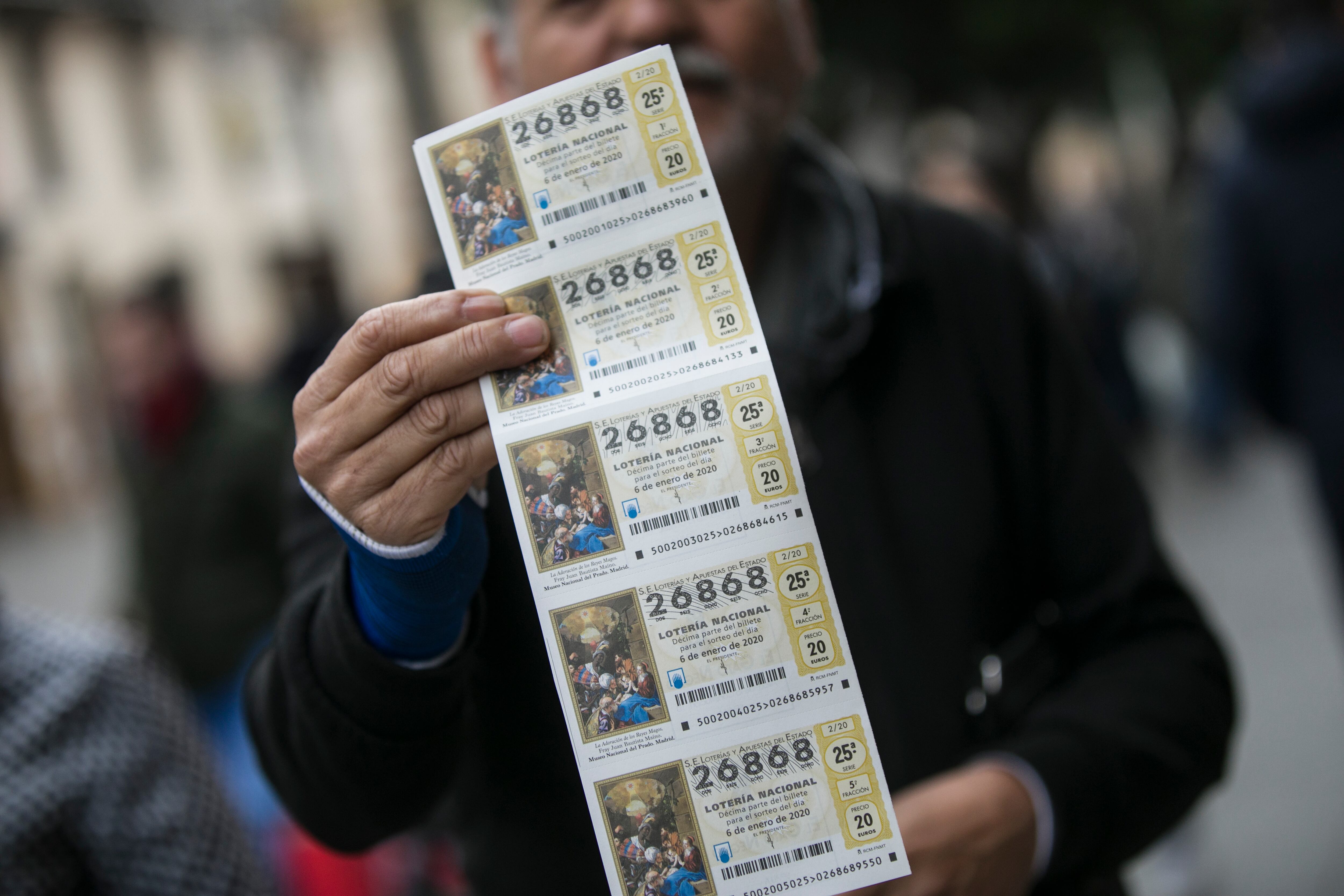 Una hombre enseña una tira de boletos de lotería (María José López / Europa Press)
