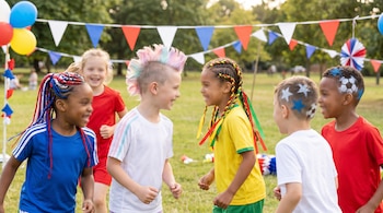 Grupo de niños sonriendo en un parque decorado con banderines. Sus peinados son coloridos con trenzas, mohawk y diseños de estrellas y balones pintados.
