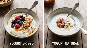 Dos tazones de yogur sobre madera: uno griego con bayas, granola y miel; otro natural con mermelada y almendras, ambos con cuchara.