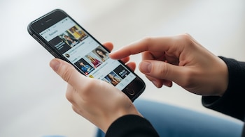 La era digital en acción: Persona navegando su smartphone - VisualesIA ScribNews