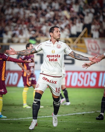Gianluca Lapadula corre con los brazos abiertos sobre el campo de juego vistiendo la camiseta crema del club Universitario