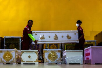 Rescue workers arrange coffins containing