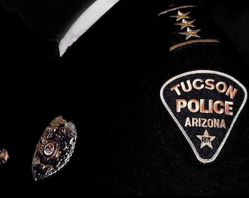 Un parche policial de Tucson y una placa metálica prendida en la chaqueta oscura de un uniforme