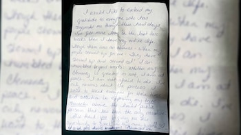 Una hoja de papel arrugada con texto escrito a mano en tinta azul y una firma en la esquina inferior sobre un fondo oscuro