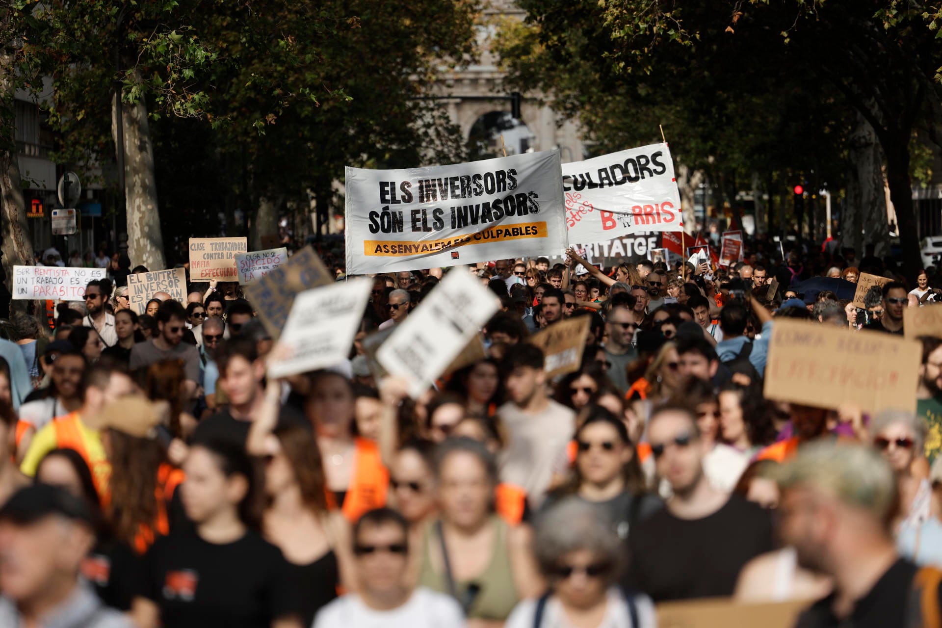 Manifestantes recorren una avenida portando carteles y pancartas con consignas sobre la vivienda y la especulación inmobiliaria.