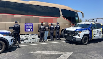 Policías estatales rodean a un detenido junto a un autobús, con paquetes de drogas en el suelo y dos vehículos policiales, un SUV y un UTV