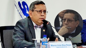 El superintendente Marco Livio Díaz Reyes, con gafas y pajarita, habla en un evento. Detrás, una bandera con logo y una imagen circular de él pensativo