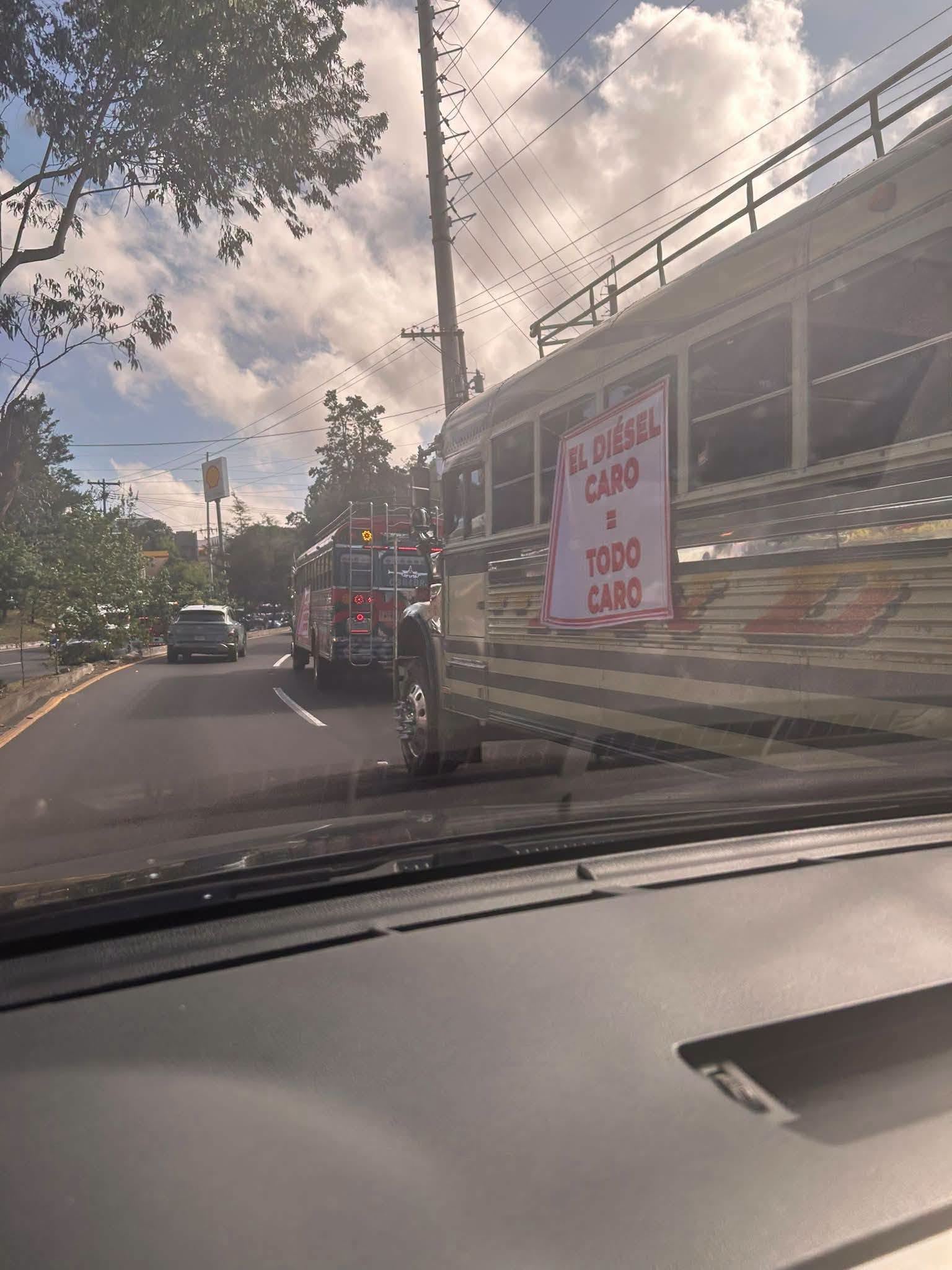 Un grupo de autobuses circula por una vía pública con letreros que reclaman por el alto precio del diésel. (Redes Sociales)