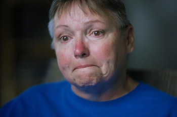 Primer plano de una mujer de mediana edad con pelo corto y rubio ceniza, llorando, con lágrimas visibles en sus mejillas enrojecidas