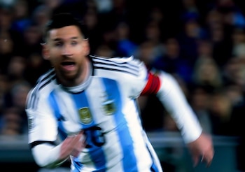 Hombre con camiseta de fútbol de Argentina con rayas celestes y blancas y el número diez, en movimiento borroso, sobre un fondo oscuro con tonos rojos