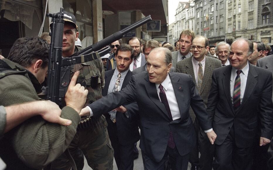 El presidente francés François Mitterrand y el presidente bosnio Alija Izetbegović caminan por una calle de Sarajevo, custodiados por personal de seguridad, durante una visita a la ciudad. (AFP/Christophe Simón)