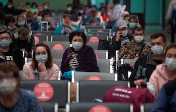 Viajeros con mascarilla esperan en