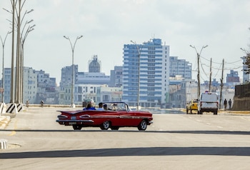 Turistas viajan en un viejo automóvil estadounidense usado como taxi por una tranquila avenida de La Habana el 8 de febrero de 2026. El gobierno cubano anunció el 6 de febrero medidas de emergencia para hacer frente a una grave crisis energética agravada por las sanciones estadounidenses, incluyendo la adopción de una semana laboral de cuatro días para las empresas estatales y restricciones a la venta de combustible. (Foto de ADALBERTO ROQUE / AFP)